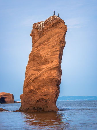 Tall Red Rock Formation with Birds in Ocean