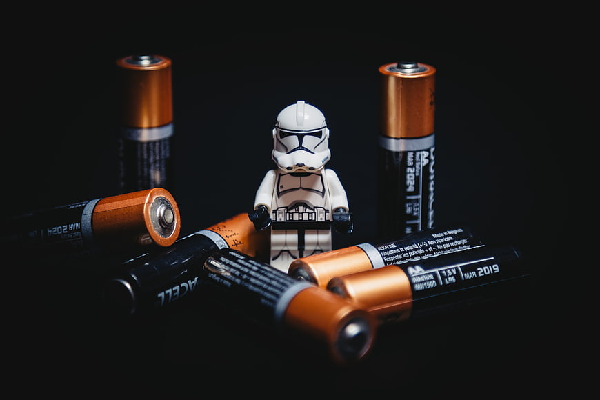 Lego Stormtrooper surrounded by AA batteries on black background