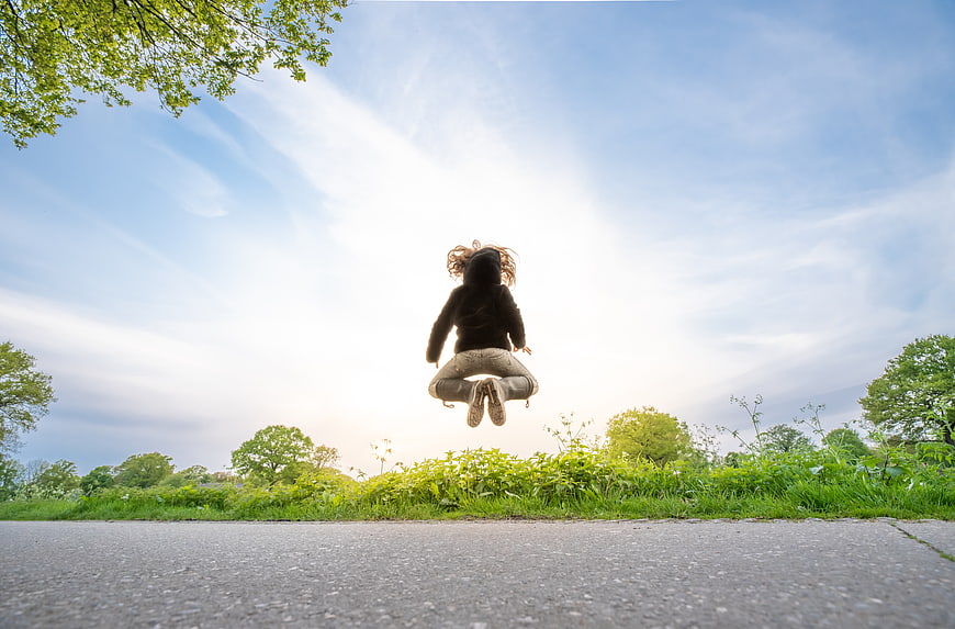 Woman jumping in the air outdoors with blue sky background