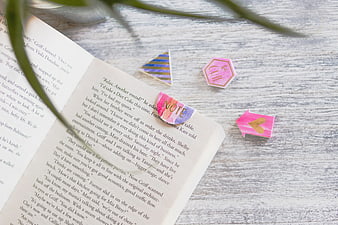 Open book with colorful bookmarks on wooden desk