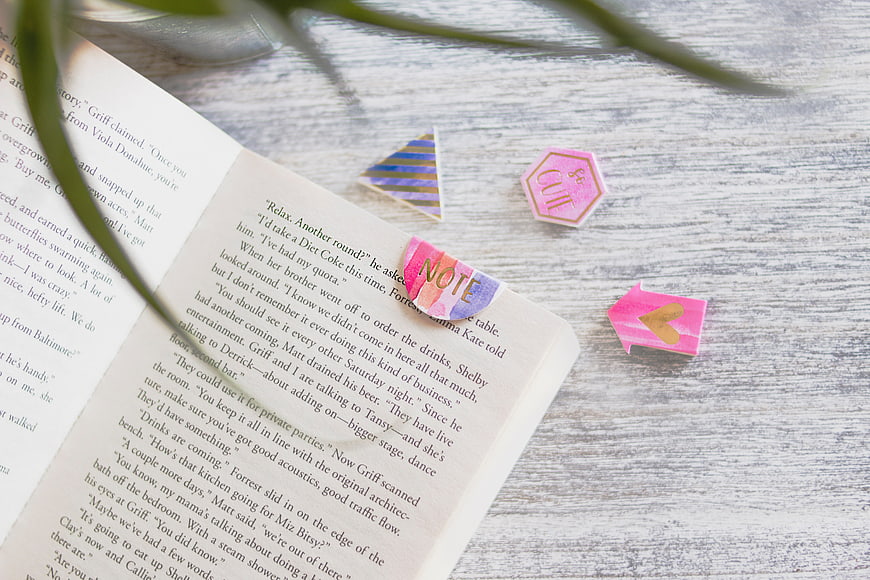 Open book with colorful bookmarks on wooden desk