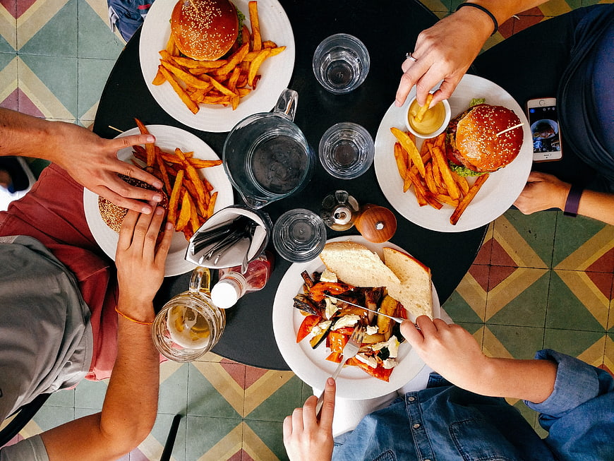 Overhead view of friends eating burgers and fries at a restaurant table