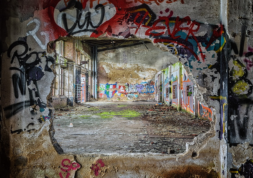 Graffiti-covered hole in abandoned building wall