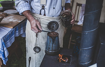 Man Brewing Coffee in Traditional Tin Pot on Wood Stove