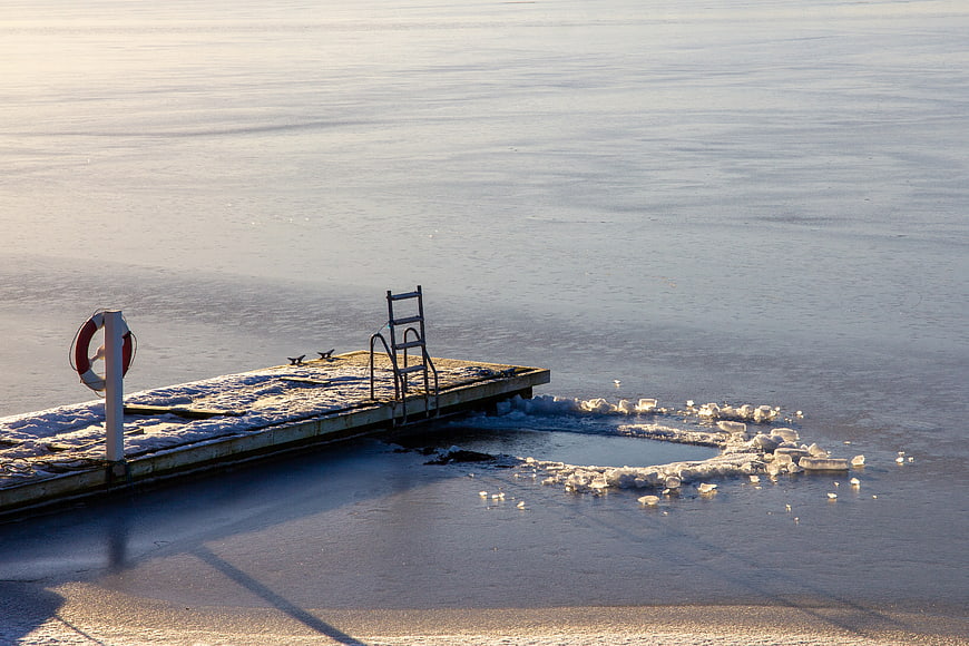 Snow-covered wooden pier on frozen lake in winter