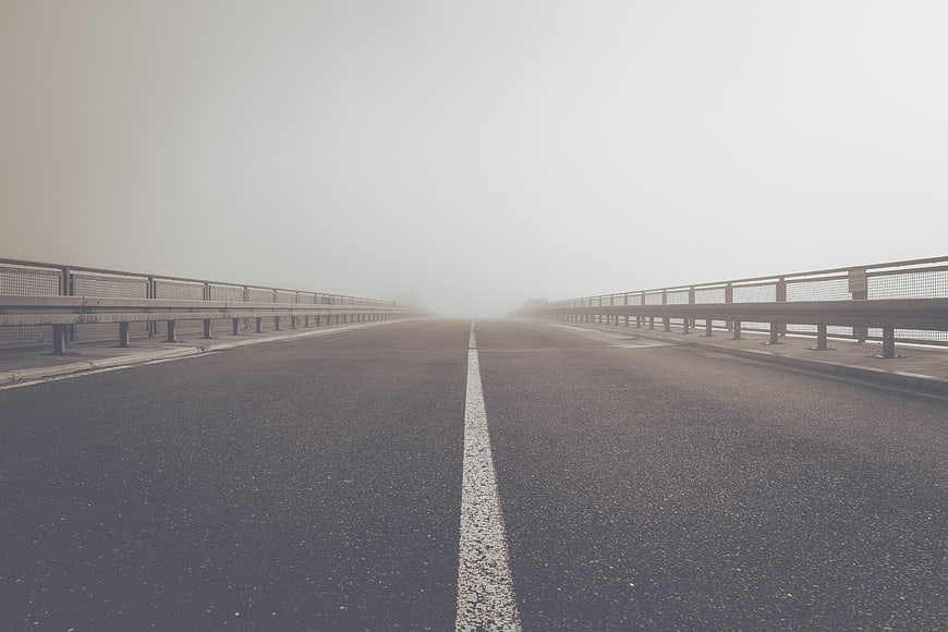 Empty foggy bridge road with white center line