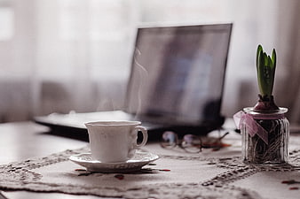 Steaming Tea Cup on Lace Tablecloth with Laptop and Plant