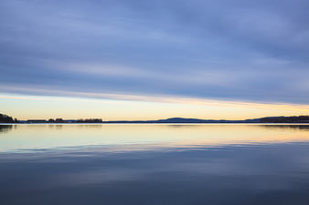 Serene Lake Landscape at Dusk with Calm Water and Distant Hills