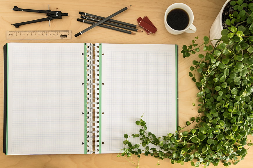 Top View of Open Notebook with Stationery and Plant on Desk