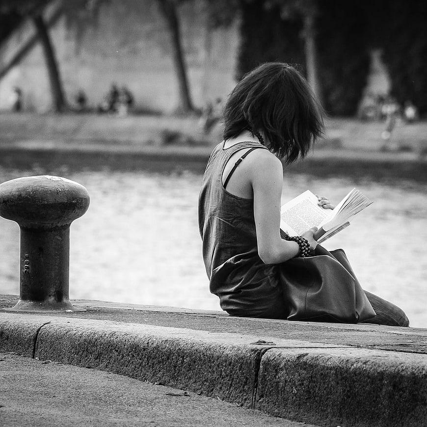 Woman Reading Book by Water in Black and White