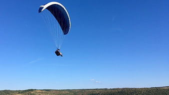 Paraglider soaring high against a clear blue sky