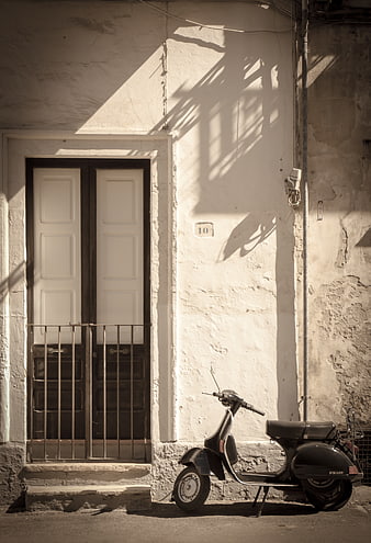 Vintage black scooter parked by a rustic Italian doorway