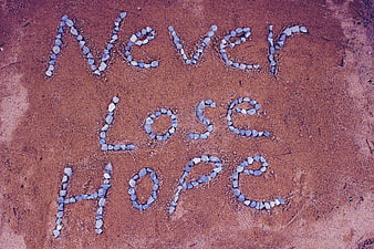 Inspirational 'Never Lose Hope' Message Spelled Out With Stones On Red Sand