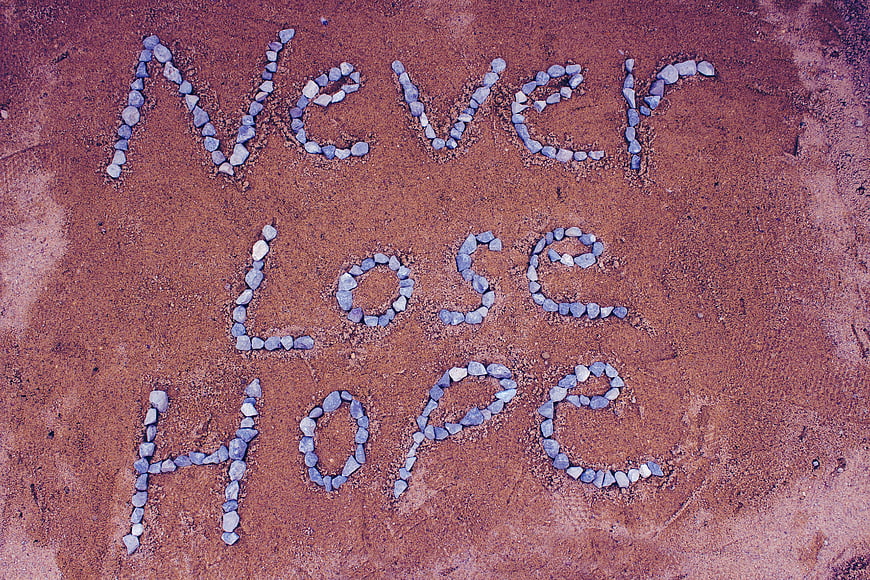 Inspirational 'Never Lose Hope' Message Spelled Out With Stones On Red Sand