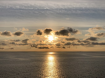 Golden Sunset Over Calm Ocean with Clouds and Reflection