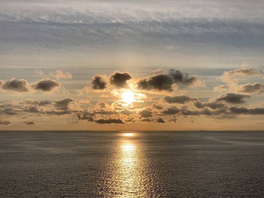 Golden Sunset Over Calm Ocean with Clouds and Reflection