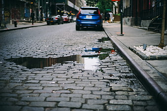 Low angle view of wet cobblestone street with puddle reflection