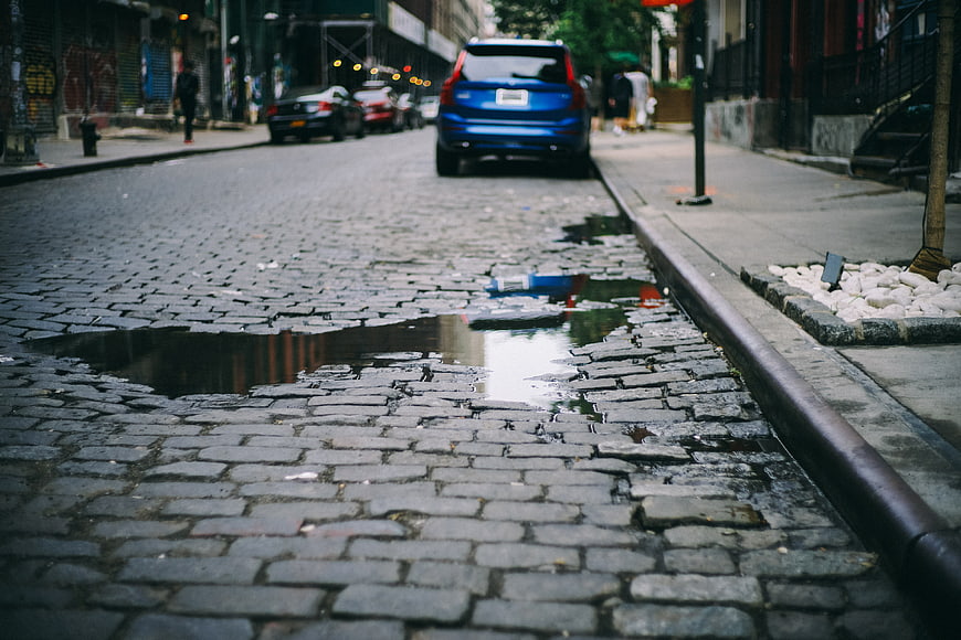 Low angle view of wet cobblestone street with puddle reflection