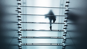 Silhouette of person walking up modern glass stairs