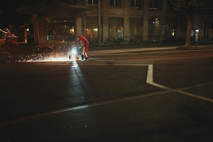 Worker grinding sparks on city street at night