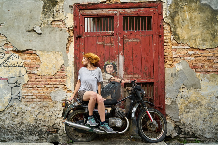 Woman sitting on motorcycle in front of red door