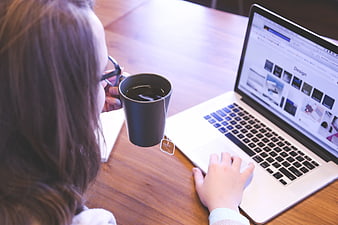 Woman drinking tea while working on laptop