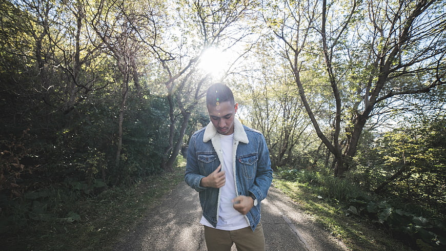 Man walking on forest path in denim jacket
