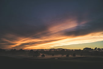 Dramatic sunset over misty rolling hills landscape