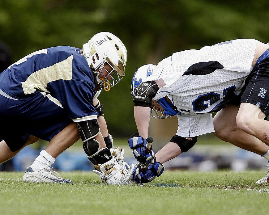 Two Lacrosse Goalies Crouching on Grass Field