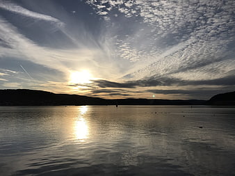 Dramatic sunset over calm lake with textured clouds