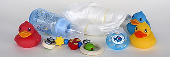 Baby care essentials with rubber ducks and toys on white background