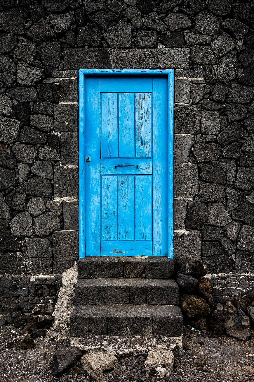 Vibrant Blue Wooden Door in Dark Volcanic Stone Wall