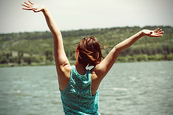 Woman with arms raised by lake enjoying freedom