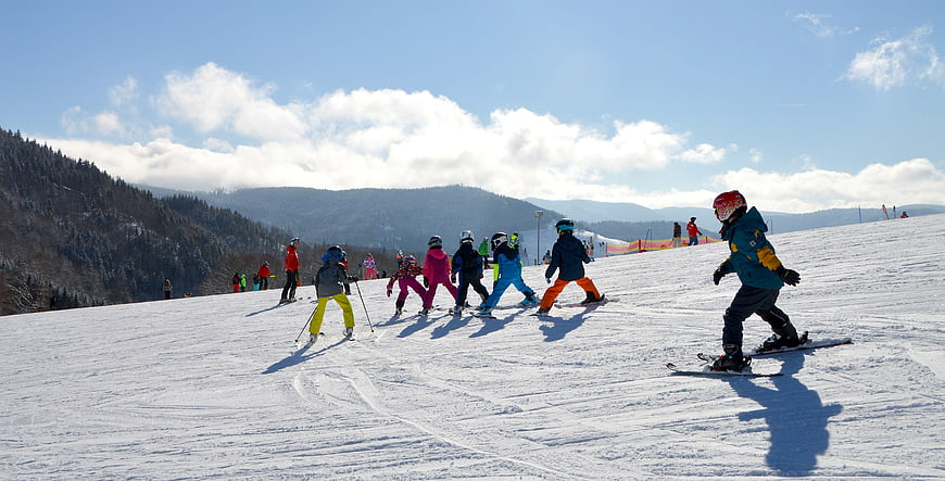 Children Skiing on a Snowy Mountain Slope in Winter