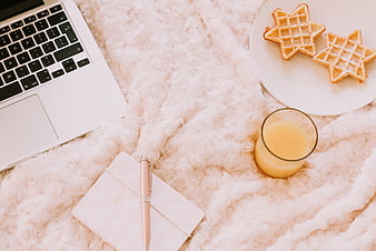 Cozy flat lay of laptop, star waffles, and juice on pink blanket