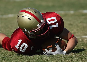 American Football Players Tackling on Grass Field