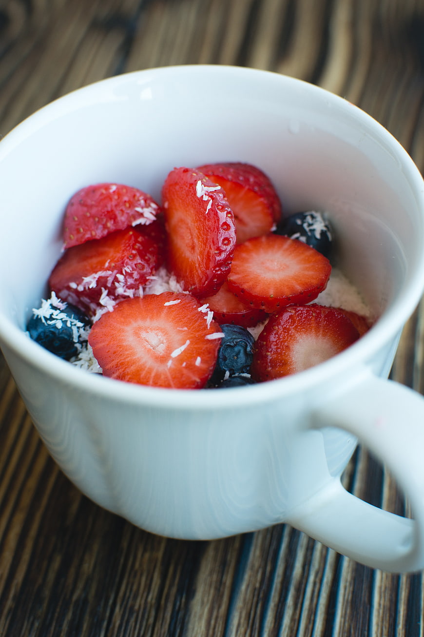 White Mug of Oatmeal with Strawberries and Blueberries