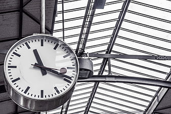 Vintage industrial clock hanging from glass ceiling structure
