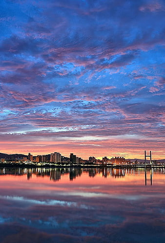 Vibrant Sunset Cityscape with Dramatic Cloud Reflections