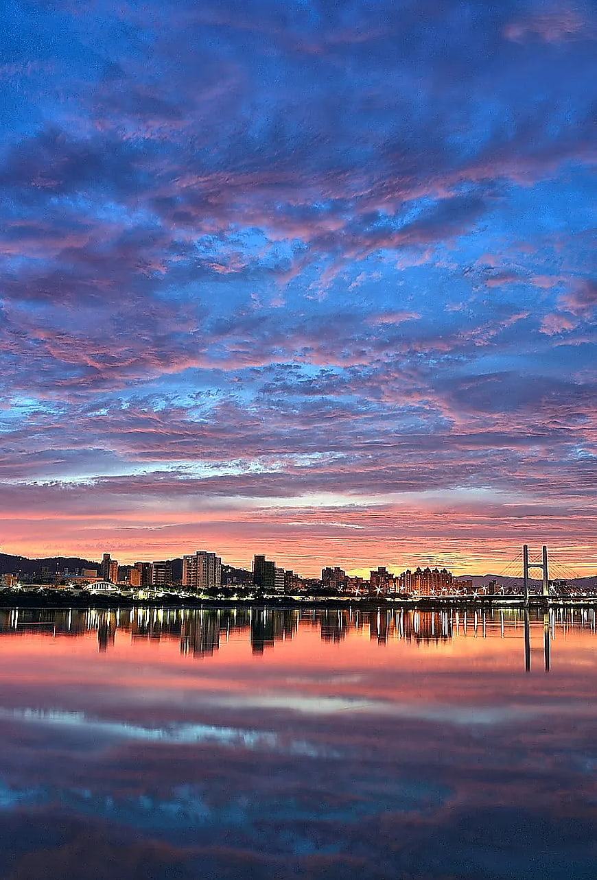 Vibrant Sunset Cityscape with Dramatic Cloud Reflections