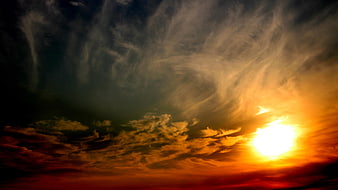 Dramatic sunset sky with swirling clouds and bright sun