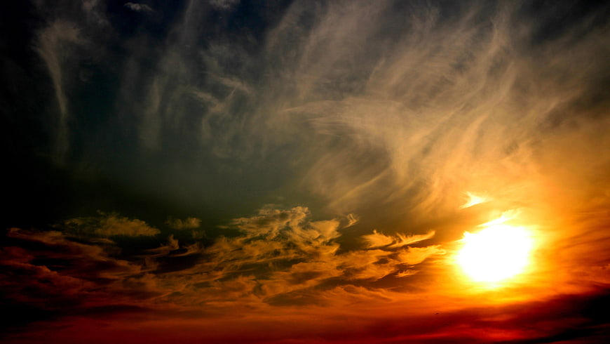 Dramatic sunset sky with swirling clouds and bright sun