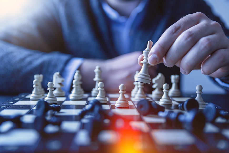 Close-up of hand moving chess piece on board