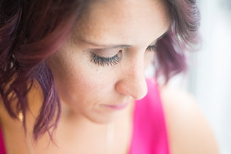 Close-up portrait of woman with purple hair looking down