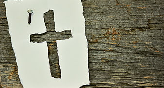 Rustic wooden cross cutout on white paper with nail