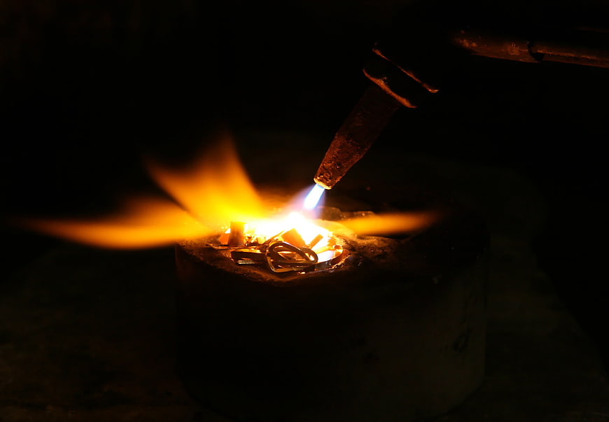Close-up of metal melting with a blowtorch in a crucible