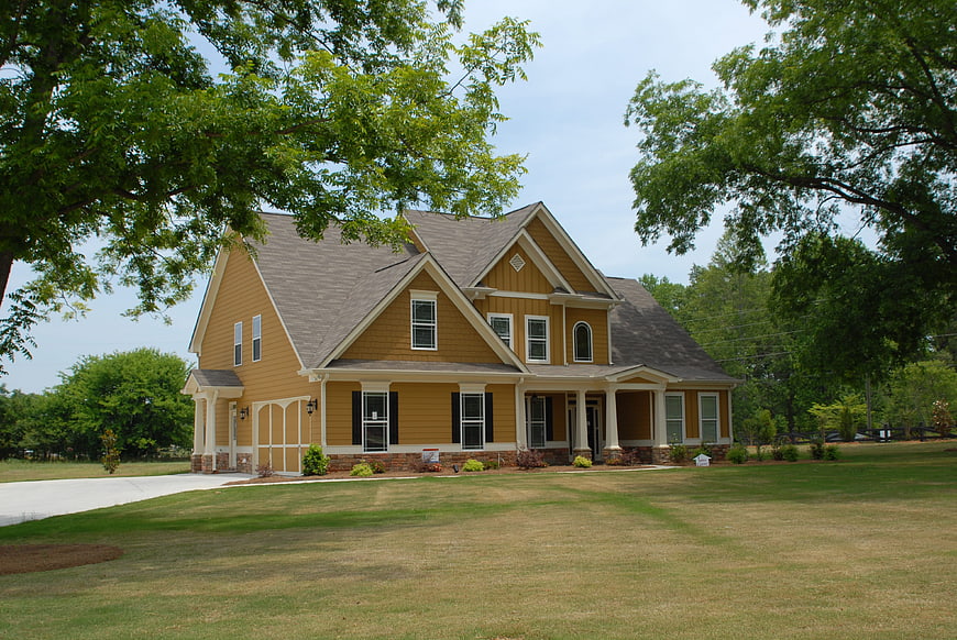 Yellow suburban house with large lawn and trees