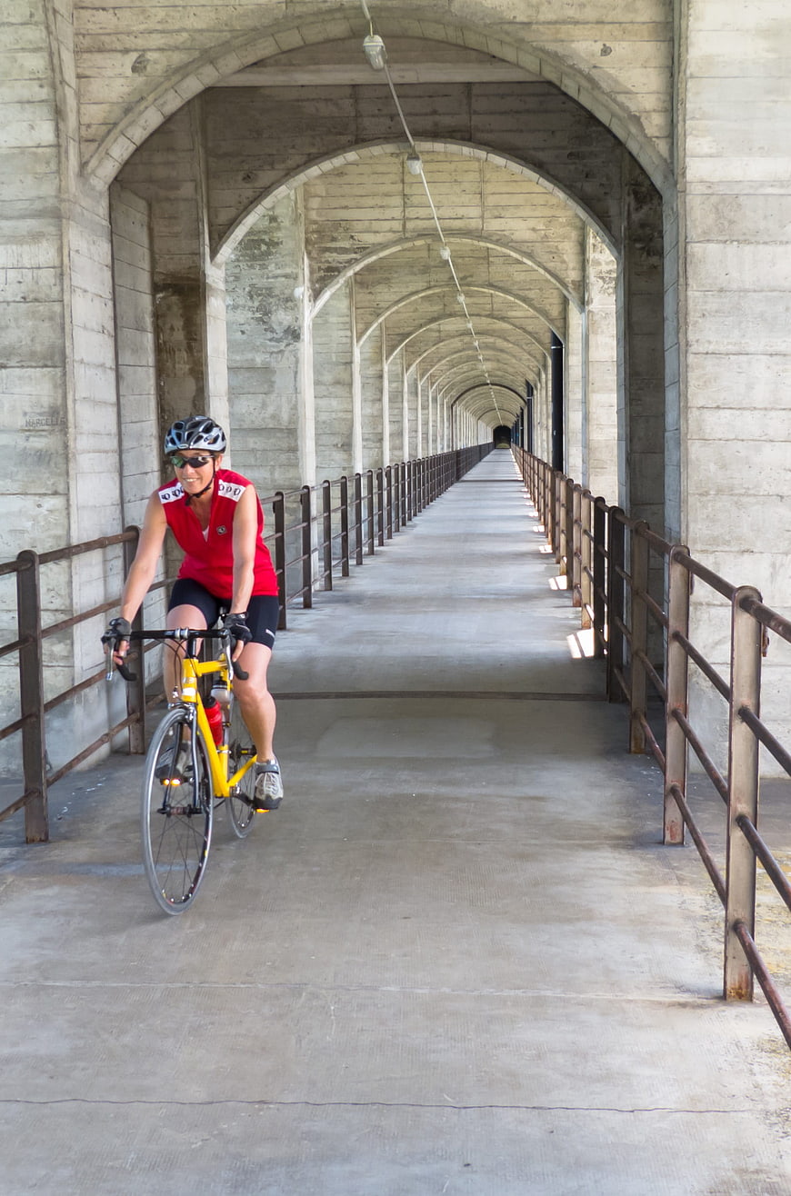 Cyclist Riding Yellow Bike Through Concrete Arch Bridge Tunnel