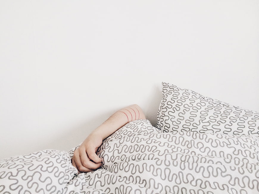 Minimalist Bedroom Scene with Patterned Bedding and Arm