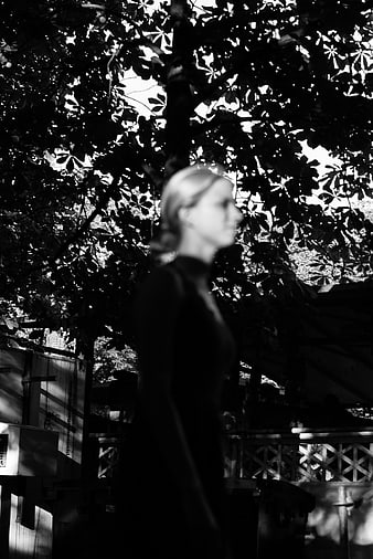 Blurred Silhouette of Woman Walking Past Trees in Black and White